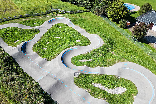 Luftaufnahme Pumptrack Wiggensbach mit geschwungenen Asphaltbahnen und grünen Inselflächen