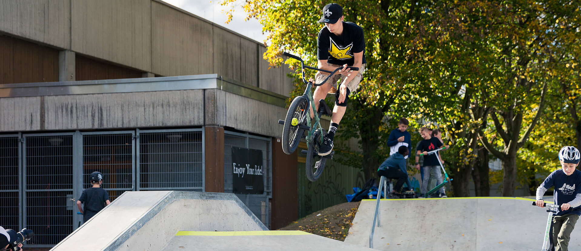 Several boys in skate park Hennef with bike and scooter