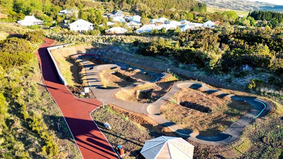 Aerial view of the complete pump track facility in Le Tampon featuring a wooden gazebo and residential area.