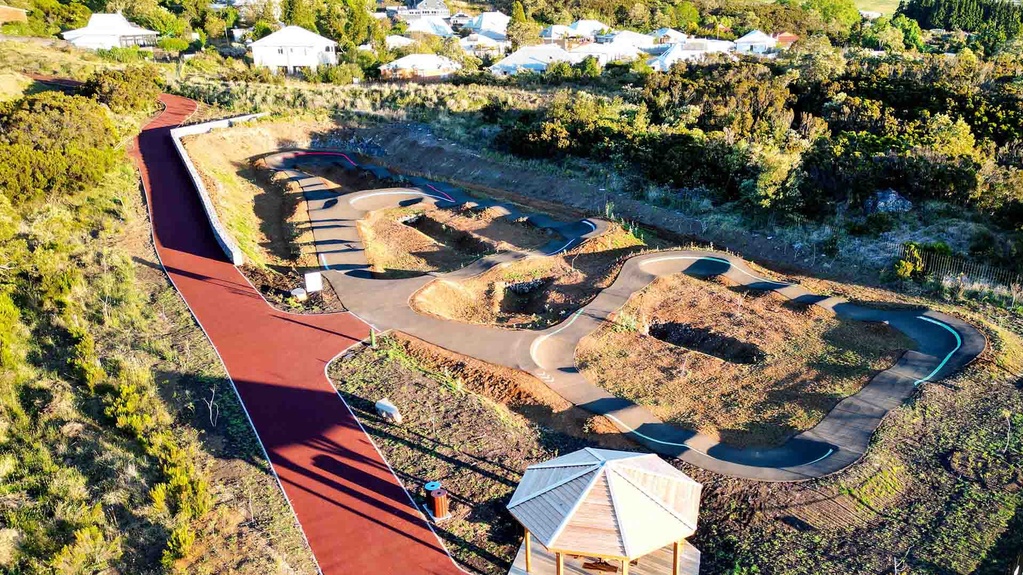 Aerial view of the complete pump track facility in Le Tampon featuring a wooden gazebo and residential area.