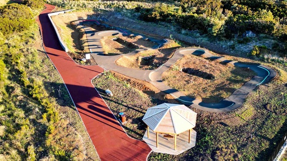 Vue aérienne du complexe de pumptrack au Tampon avec kiosque en bois et habitations environnantes.