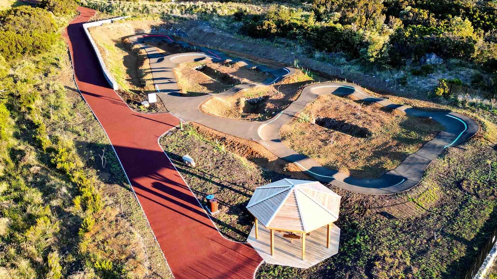 Vue aérienne du complexe de pumptrack au Tampon avec kiosque en bois et habitations environnantes.