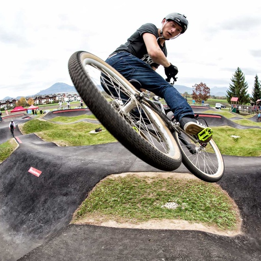 Mann mit Fahrrad macht einen Jump auf Jumptrack