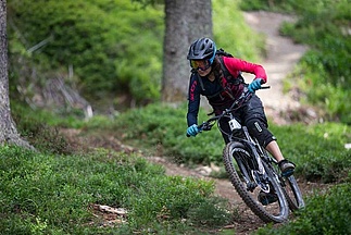 [Translate to Französisch:] Mountainbikerin auf flachem Trail im Wald