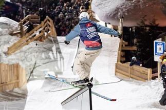 Skifahrer fährt ein Rail vor einer Zuschauermenge herunter