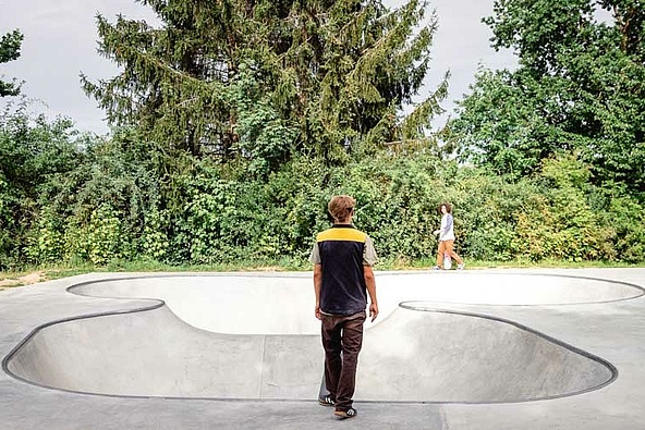 Skateboarder mit schwarzgelber Weste steht vor Ortbeton Bowl