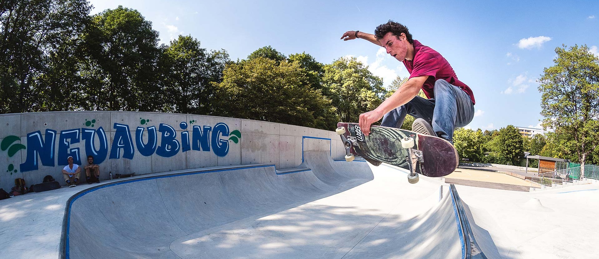 Skateboarder mit rotem T-Shirt macht Trick in Skatepark