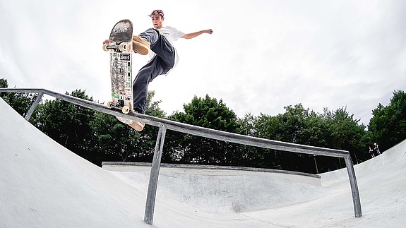 Skateboarder performing a trick on a rail in a skate park