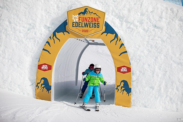 Zwei Kinder fahren auf Ski durch Tunnel