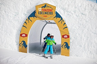 Zwei Kinder fahren auf Ski durch Tunnel