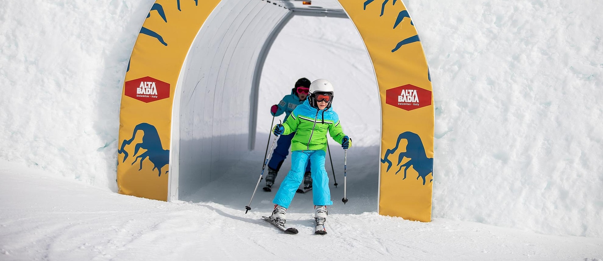 Two children skiing through tunnel