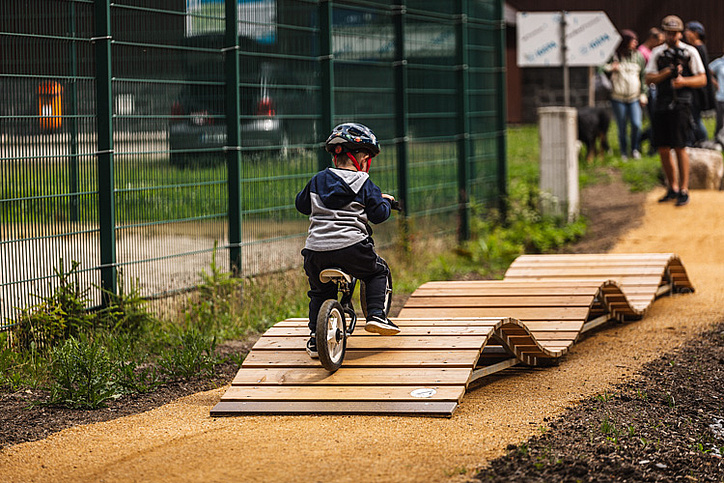 Kleinkind auf Laufrad über Wellenbahn im MTB-Park Rabenberg