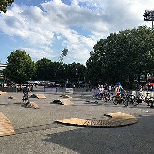 [Translate to Chinesisch:] Various exercise elements on an asphalt square with trees