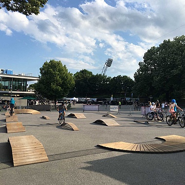 Various exercise elements on an asphalt square with trees