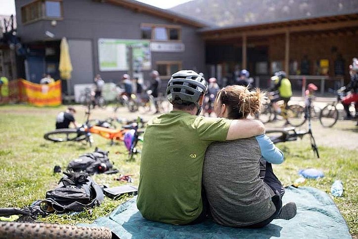 Couple sitting in lounge area by lift in front of many bikes