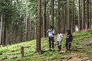 [Translate to Französisch:] Drei Männer stehen im Wald und begutachten das Gelände