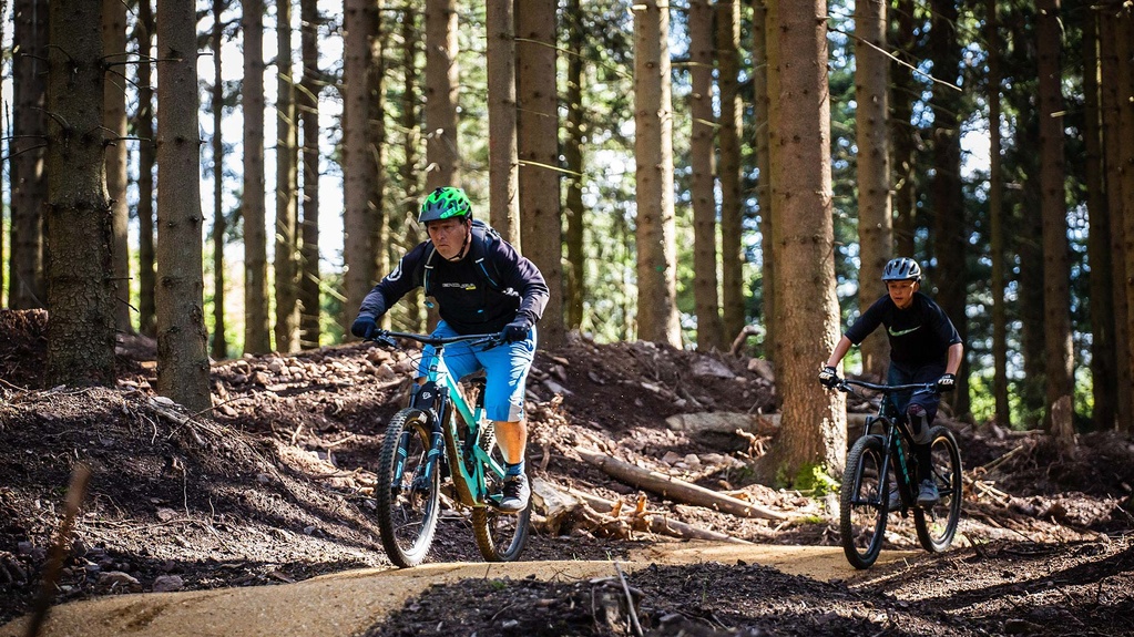 Father and son ride on straight track in bike park