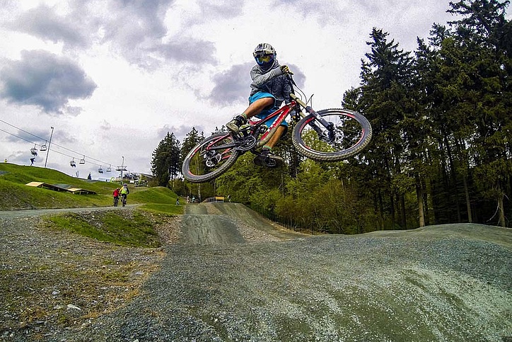Biker jumps towards camera and lift in the background