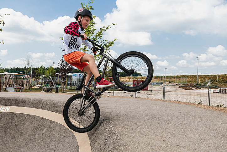 Boy on bike does a trick over the edge from pump track