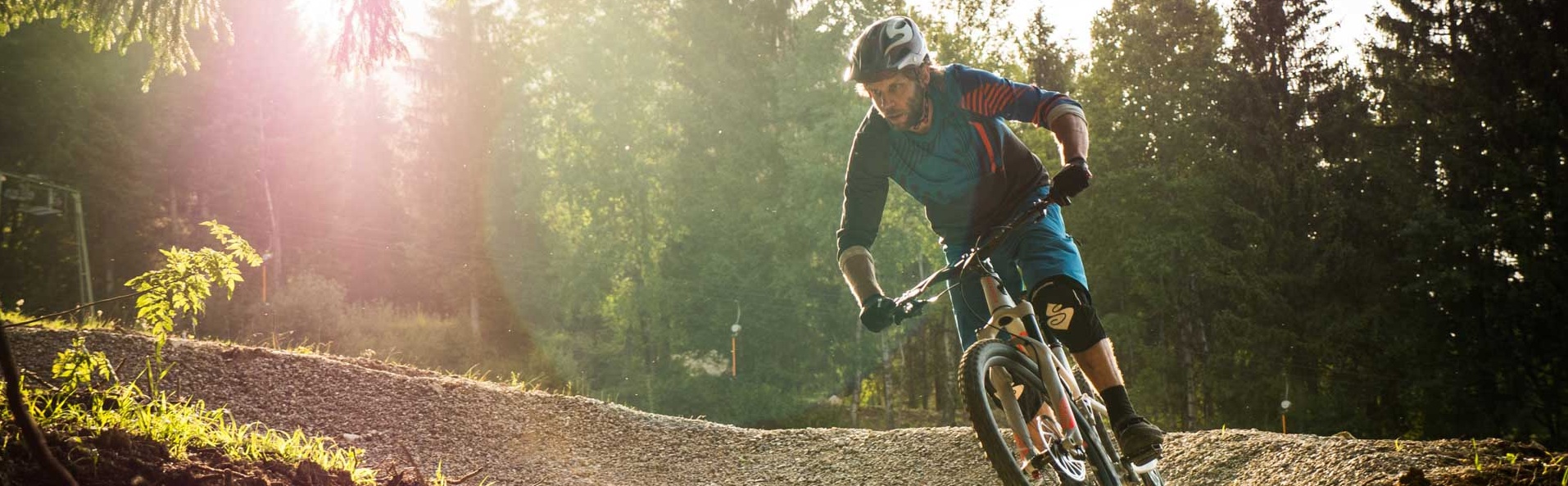 Mountain biker in a curve on a flow trail at the edge of the forest