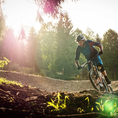 Mountainbiker in einer Kurve auf einem Flowtrail am Waldrand