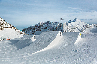 Skier after jump in air in front of mountain panorama
