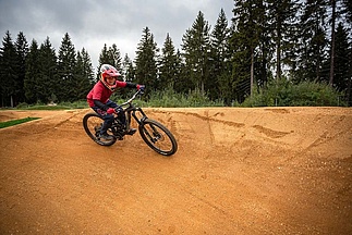 Child with protective gear takes a turn on the pump track