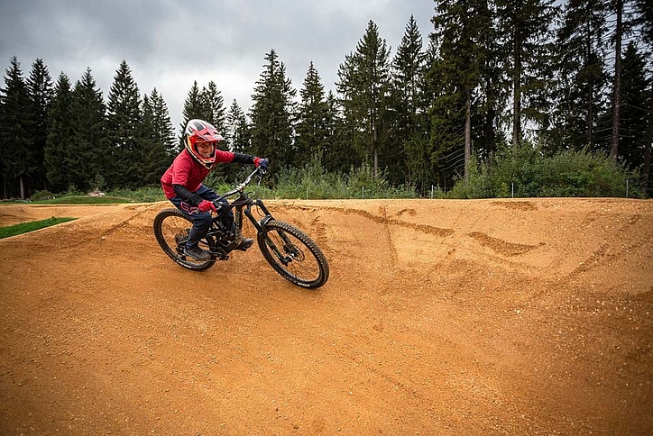Child with protective gear takes a turn on the pump track