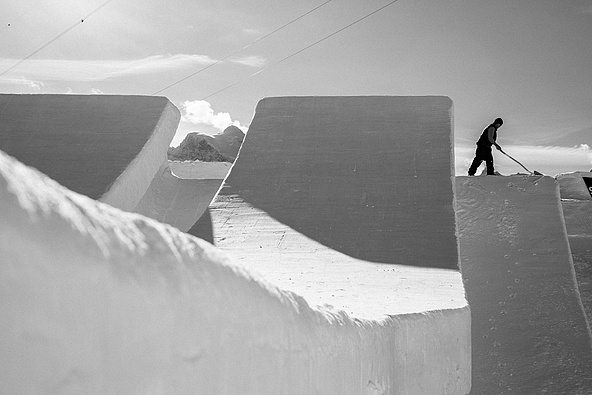 Schwarz-Weiß-Aufnahme eines Shapers beim Feinschliff eines Swatch Snowpark Kickers am Schilthorn.