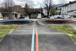 Frontalansicht einer Asphalt-Pumptrack-Anlage in Saint-Girons mit blauen und roten Bodenmarkierungen.