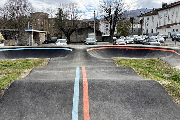 Frontalansicht einer Asphalt-Pumptrack-Anlage in Saint-Girons mit blauen und roten Bodenmarkierungen.