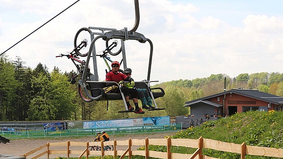 Two mountain bikers ride up chairlift