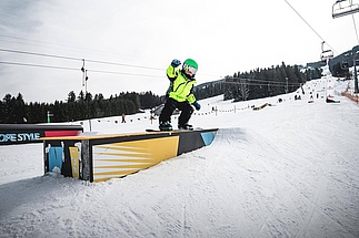 Child rides his snowboard over a box