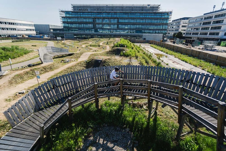 Biker fährt Kurve bergauf vor Bürogebäude