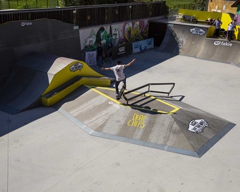 A skateboarder performing a trick on a rail over a ramp obstacle at the Meran skatepark.