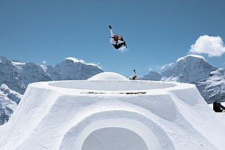 Freestyler zeigen Sprünge über den Swatch Bowl und Holzrampen am Schilthorn vor winterlicher Kulisse.