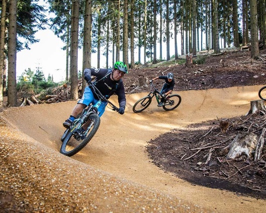 Bikepark Oberhof Two bikers ride a turn on a newly built bike park in the forest