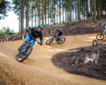 Two bikers ride a turn on a newly built bike park in the forest