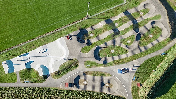 Drohnenaufnahme des gesamten Parks mit Skatepark und Pumptrack in direkter Nachbarschaft zu einem Fußballfeld.