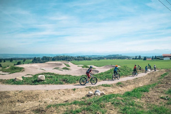 Children's group rides mountain bikes towards the pump track 