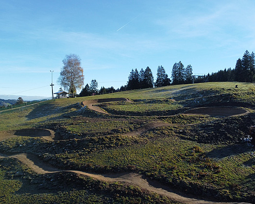 Wide view of Bikepark Weitnau with switchbacks and trails on green hillside