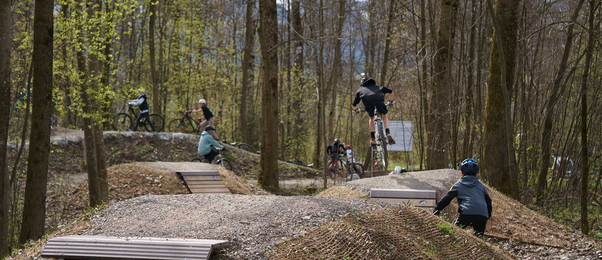 Several mountain bikers riding and jumping over features in Sonthofen bike park