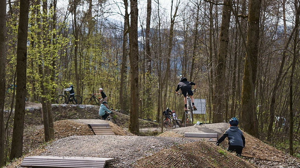 Mehrere Mountainbiker fahren und springen über Hindernisse im Bikepark Sonthofen