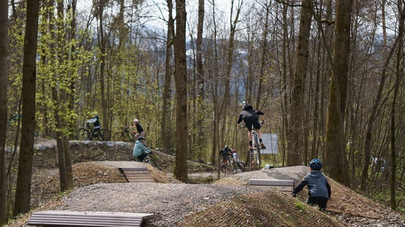 Several mountain bikers riding and jumping over features in Sonthofen bike park