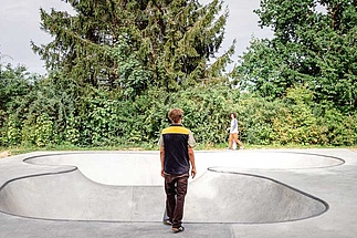 Skateboarder with black and yellow waistcoat stands in front of Ortbeton Bowl