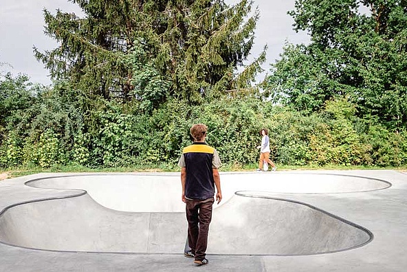 Skateboarder with black and yellow waistcoat stands in front of Ortbeton Bowl