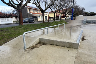 Metall-Rail auf einer Betonrampe im Skatepark Biscarrosse bei nassem Wetter und kahlen Bäumen.