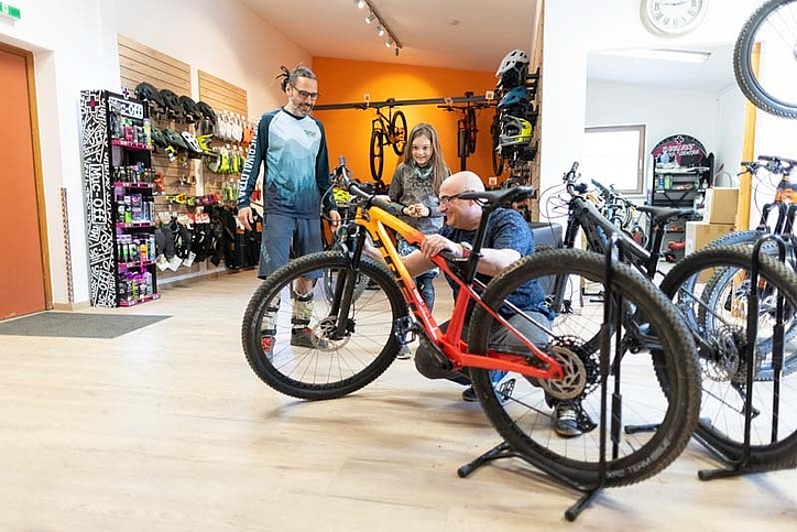 Three people in a bike store looking at a mountain bike