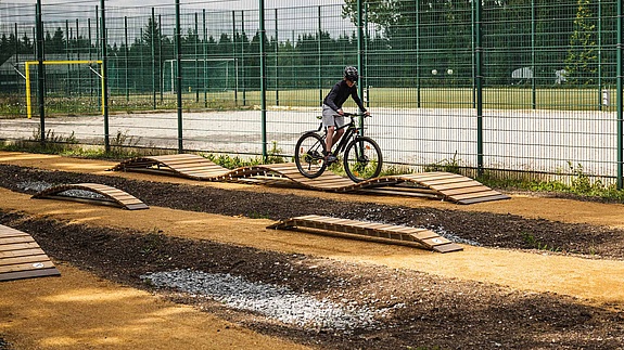 Rider testing wooden elements on skills course at MTB Park Rabenberg