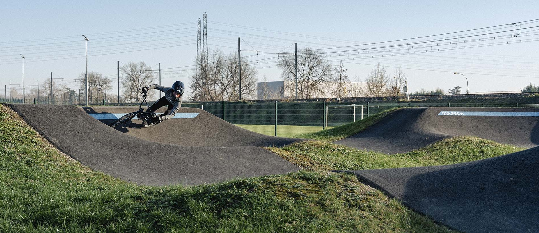 Mountainbiker fährt sportlich in einer markierten Steilkurve auf einer asphaltierten Pumptrack-Anlage.